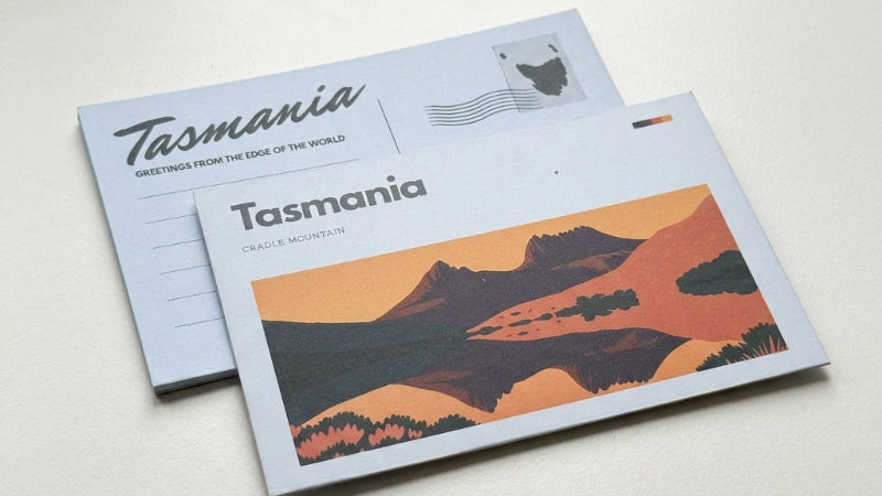 Two postcards with 'Tasmania' text and mountain illustration on a light gray background